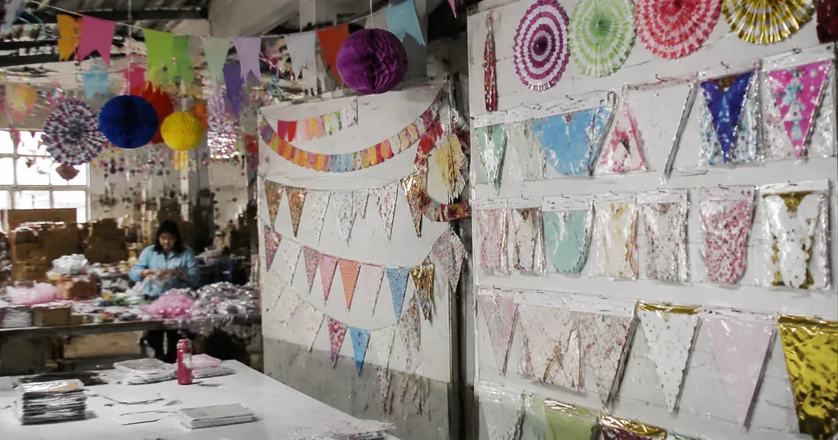 Christmas-themed party supplies including red and green bunting, snowflake decorations, holiday balloons, and festive tableware on a factory display table
