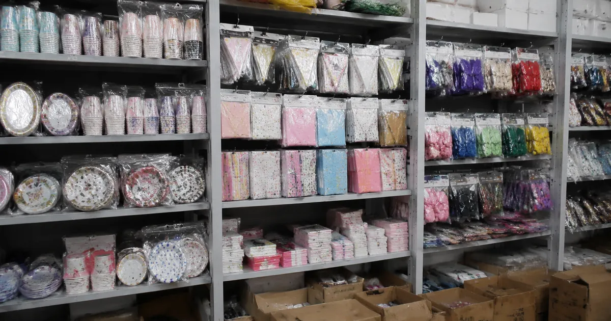 Coordinated party supply collection with matching balloons, cups, plates, banners, and gift bags in one unified theme on a factory display table