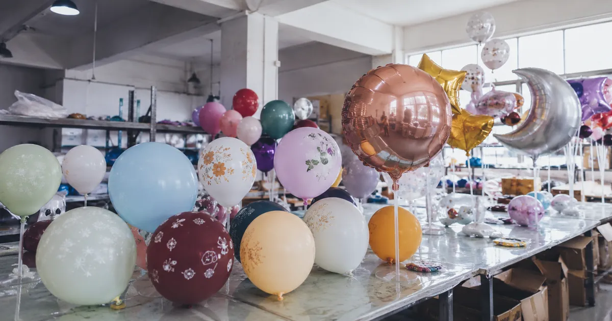 Comprehensive display of different balloon types, shapes, and sizes arranged on a factory sample table for buyer reference
