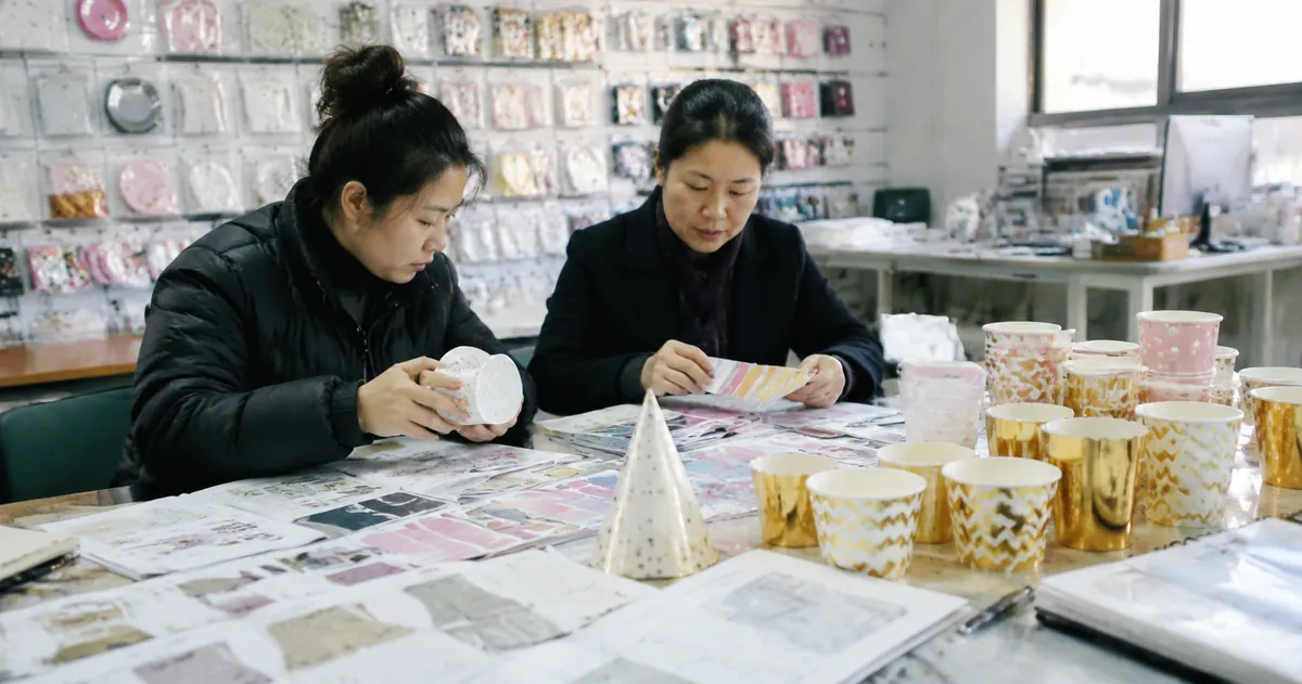 Comparison display of different printing methods on party supplies — screen print, offset, flexo, and digital print samples on a factory inspection table